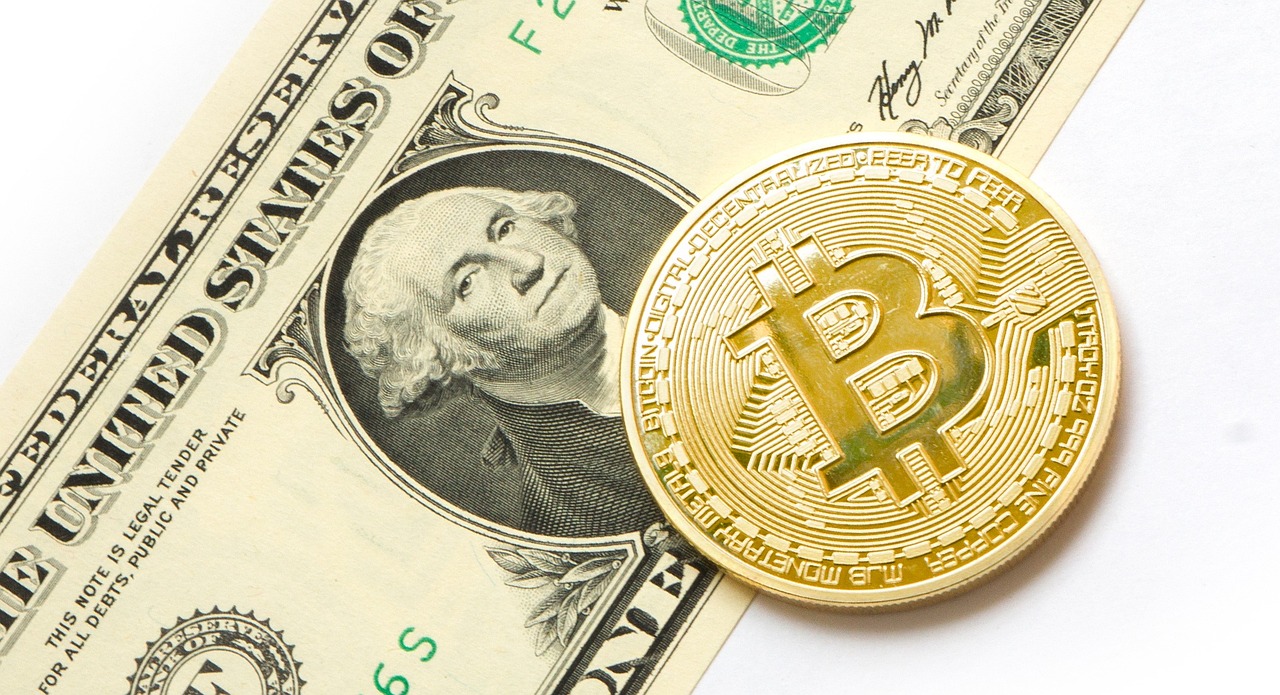 عملة بيتكوين ذهبية فوق ورقة دولار أمريكي، تعبر عن العلاقة بين البيتكوين والعملات التقليدية والقيمة السوقية المتزايدة للبيتكوين.